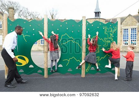 Children On Climbing Wall In School Playground At Breaktime