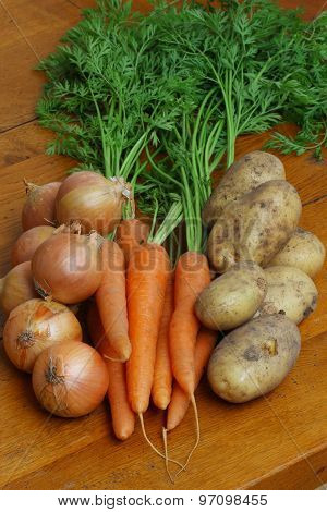 Onions, Carrots & Potatoes on a Wooden Kitchen Table