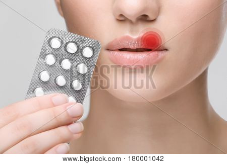 Young woman with pills near face, closeup. Herpes virus concept