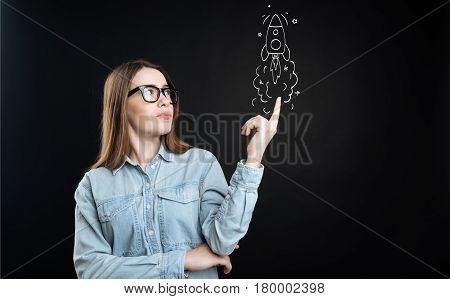 Start it up. Pleasant delighted young woman launching the rocket while having brillian ideas