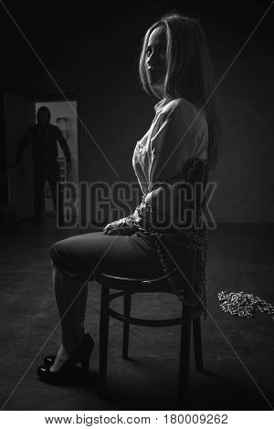 Evil is coming. Captured powerless scared woman sitting tied up to a chair in some strange place and trying figuring out what happening