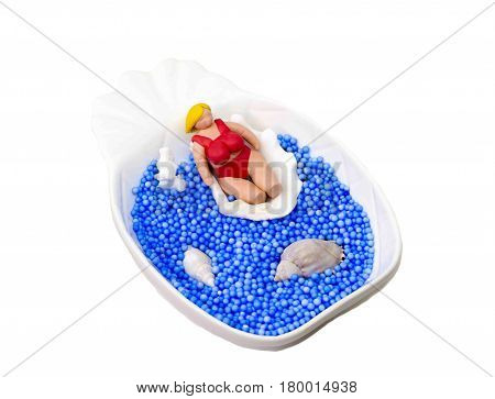 Handmade miniature doll in red bikini on white background. Puppet scene of fat tourist relaxing by sea. Blonde woman in swimming suit. Big girl body positive concept. Summer vacation model macro photo