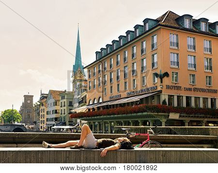 Man Relaxing At Limmatquai And Fraumunster Zurich