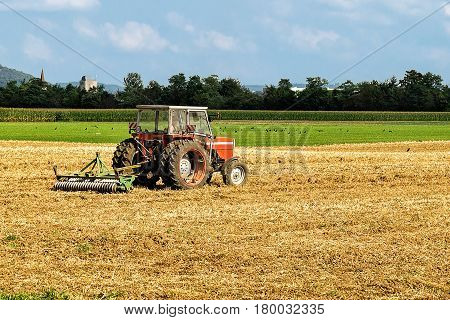 Tractor with plough doing agricultural seasonal work in the field.