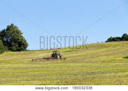 Tractor with plough doing some agricultural seasonal work in the field.