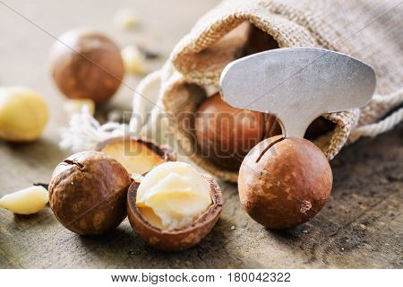 Macadamia Nuts With Metal Opener On Wooden Board