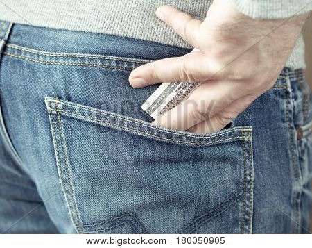 his hand put dollars in jeans pocket or take out from pocket