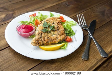 served Homemade Breaded Schnitzel with salad and berry sauce on old wooden table