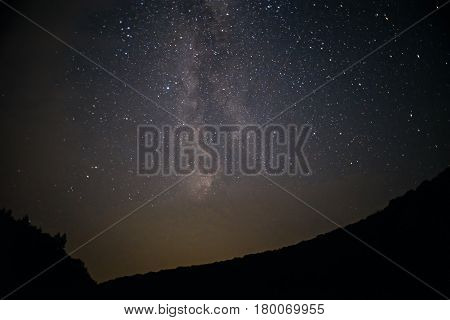 A Clear Night Sky With A Hill And Trees In The Foreground