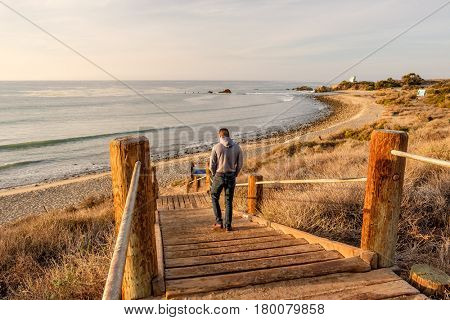 Man walking at boardwalk to Leo Carrillo State Beach, Malibu, California.
