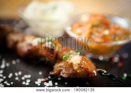 Iberian pork shish kebab with onion salad and sauce seved on a stone board