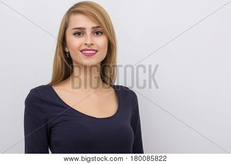 Fashion portrait of a girl posing in bright, spacious studio with a gray background in a stylish comfortable and simple clothes. young girl with clean skin and perfect face