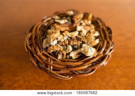 Walnut kernels in snall wicker basket on wood