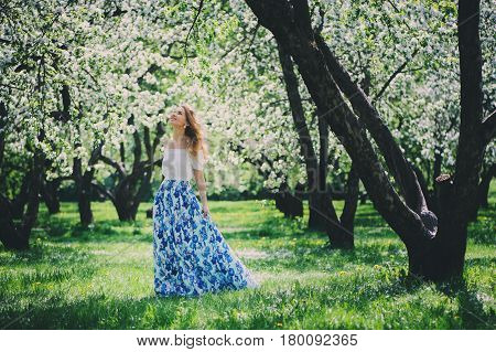 beautiful young woman in floral maxi skirt walking in spring