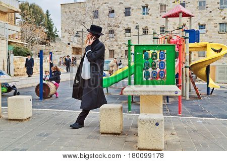 JERUSALEM, ISRAEL - DECEMBER 29, 2016: Orthodox Jewish man with mobile phone walk at street at the playground in jewish quarter. 