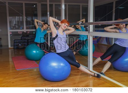 two Young sporty girls doing exercises with pilates ball in gym. Healthy lifestyle