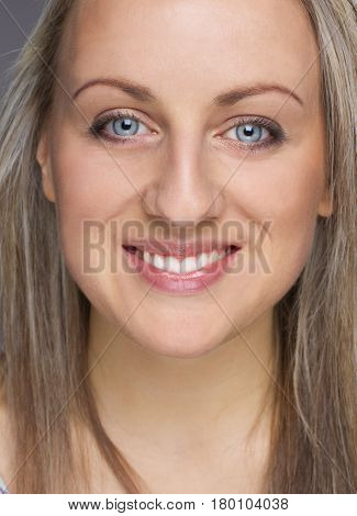 Close-up portrait of young happy blonde woman smilling