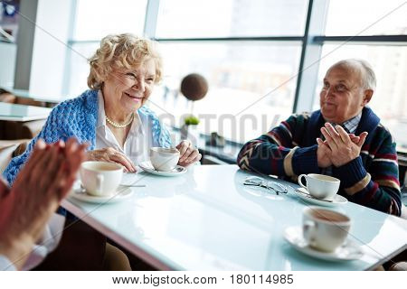 Senior people applauding joyfully to pretty woman after her self-introduction during personal development workshop in pleasant atmosphere
