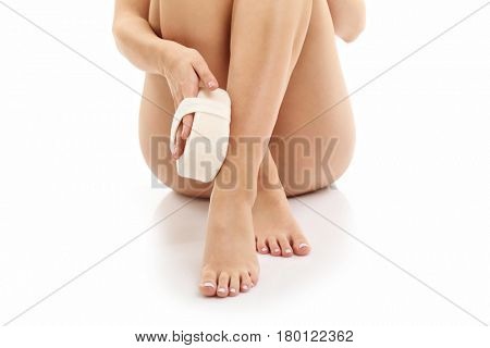 Woman legs with bath sponge isolated on white with healthy skin