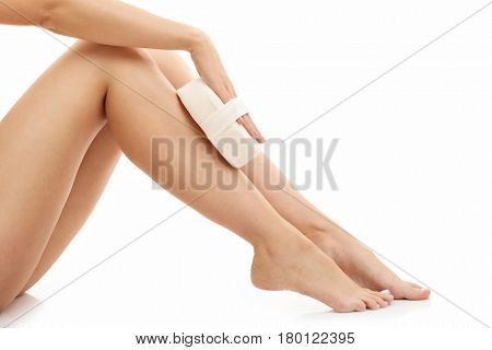Woman legs with bath sponge isolated on white with healthy skin