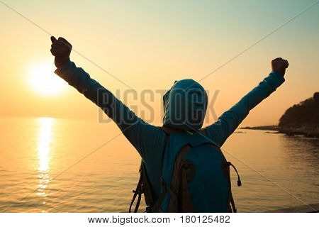 Happy woman with open arms at sunset on beach