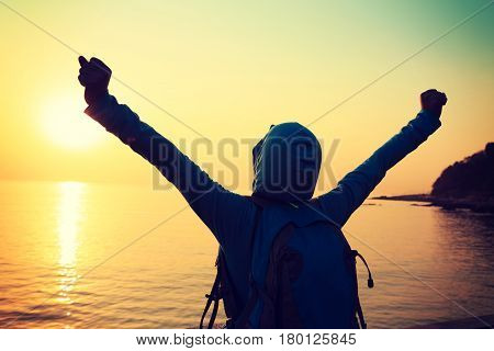 Happy woman with open arms at sunset on beach