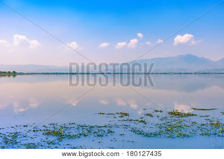 calmness lake in the morning with mountain and reflection in the water Kwan Phayao or Phayao Lake Northern of Thailand
