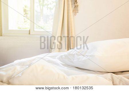 white pillow and blanket with wrinkle messy on bed in bedroom with lighting upper left side from sleeping in a long night winter.