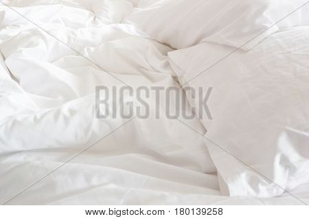 wrinkle messy blanket and white pillow in bedroom after waking up in the morning from sleeping in a long night details of duvet and blanket an unmade bed in hotel bedroom with white blanket.