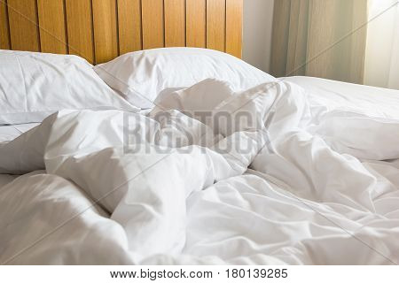white pillow and blanket with wrinkle messy on bed in bedroom with lighting upper left side from sleeping in a long night winter.
