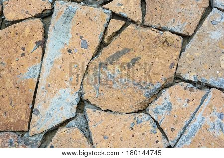 Close up wall covered with pieces of light brown stone forming mosaic pattern abstract texture background