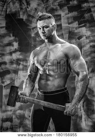 athlete and hammer. guy with a nice toppless muscle fitness body, bodybuilder coach hold big metal hammer