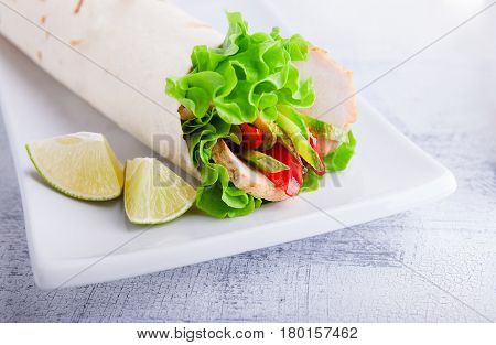Sandwich wrap with garden salad, chicken, lettuce and tomato in a whole wheat tortilla