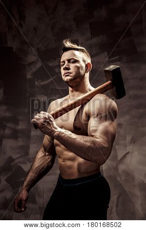 athlete and hammer - a very beautiful young guy with a nice muscle fitness and bodybuilder coach hold in strong arms and big metal hammer