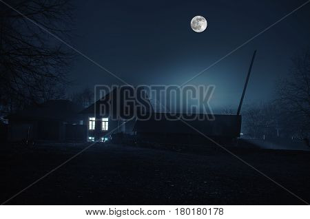 House In Fog At Night In The Garden, Landscape Of Ghost House In The Dark Forest With Big Full Moon