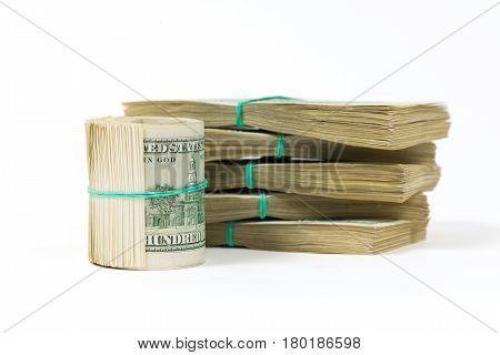 A twisted bundle of 100 dollar bills stands on packs of dollars. Isolated on white.