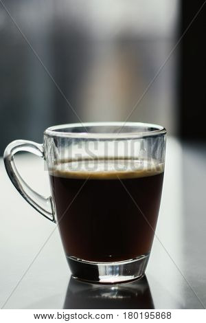 Black espresso coffee with heady froth in a glass mug or cup