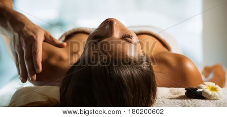 The beautiful young girl relaxes in the spa and gets massage