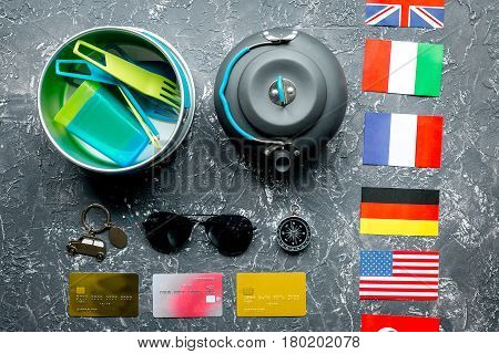 traveller lifestyle items with compass and plactic dishes on gray table background top view