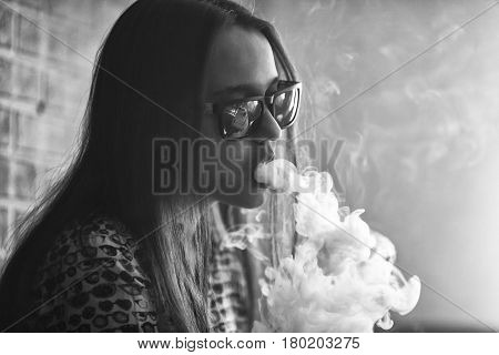 Vape. Young Handsome White Girl In Sunglasses Is Admiting Puffs Of Steam From The Electronic Cigaret