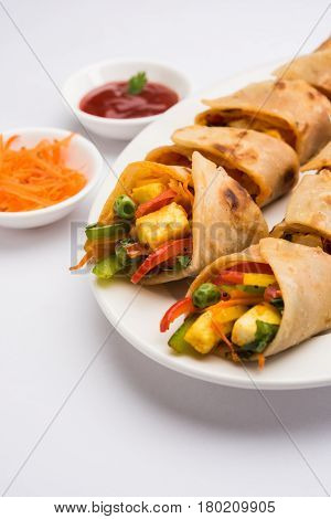 Indian popular snack food called Vegetable spring rolls or veg roll or veg franky made using paneer or cottage cheese and vegetables wrapped inside paratha/chapati/roti with tomato ketchup.