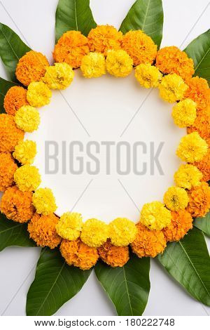 flower rangoli made using marigold or zendu flowers and mango leaves over black background with copy space in the middle, selective focus