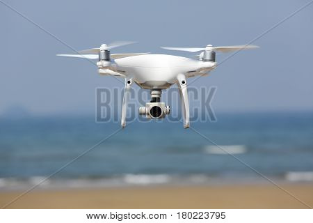 KAGAWA, JAPAN - APRIL 03, 2017: White remote controlled Drone Dji Phantom4 Pro equipped with high resolution video camera hovering in air with shore and blue sky in the background