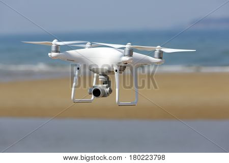 KAGAWA, JAPAN - APRIL 03, 2017: White remote controlled Drone Dji Phantom4 Pro equipped with high resolution video camera hovering in air with shore and blue sky in the background