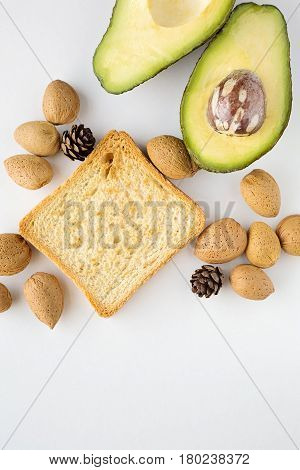 Sliced avocado oats toast and whole almonds view from above white background breakfast
