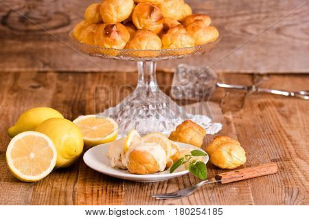Profiteroles with lemon cream on white dish.