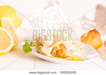 Profiteroles with lemon cream on white dish.