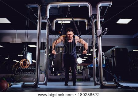 A man is doing exercises on  simulator in the gym.