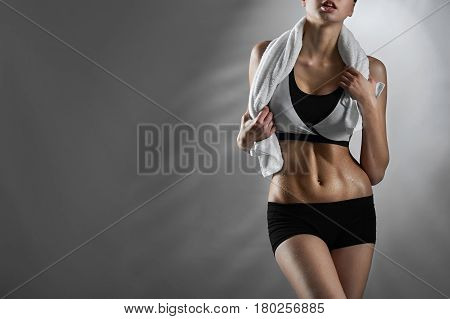 Feeling fit. Female fitness trainer wearing sports clothing posing with a towel around her neck on blue background looking away copyspace on the side