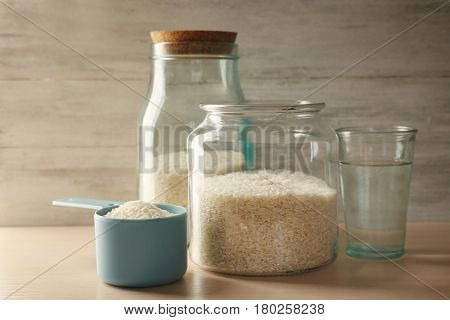 Kitchen ware with rice and water on wooden table